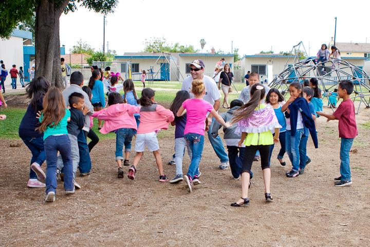 A large group of children are gathered together running around in this example of tag games.