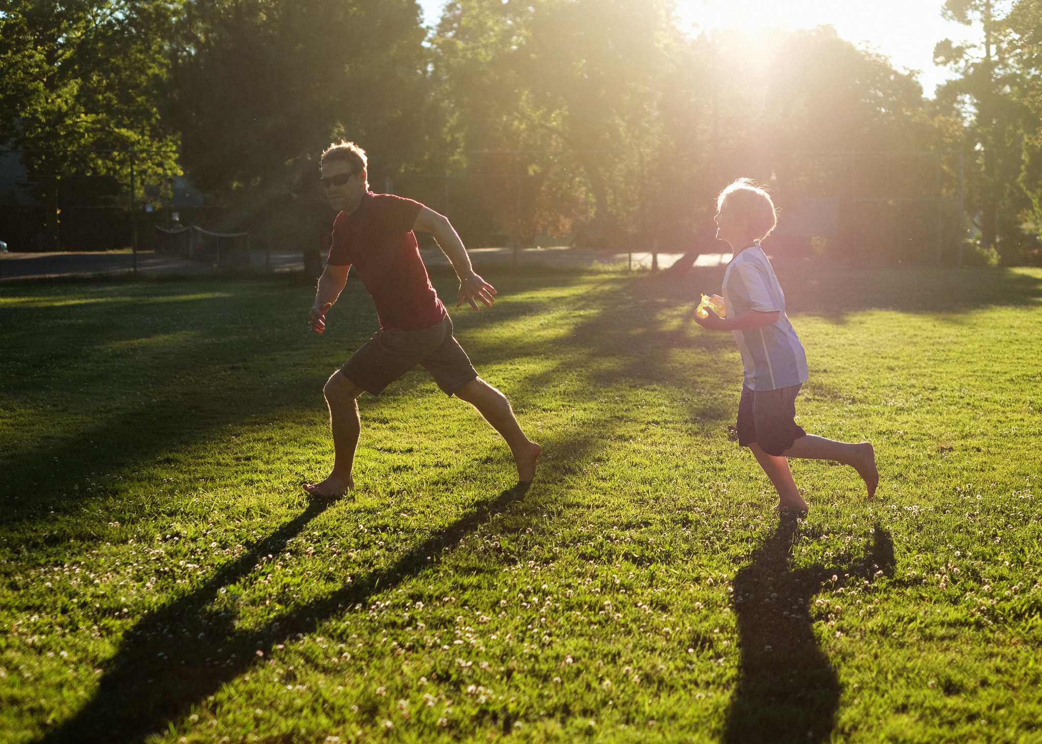 A man and a child are shown chasing their shadows outside in this example of tag games.